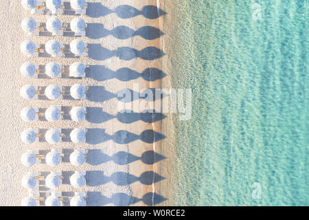 Vue de dessus, superbe vue aérienne d'une incroyable plage blanche vide avec parasols blancs et turquoise de l'eau claire pendant le coucher du soleil. Banque D'Images