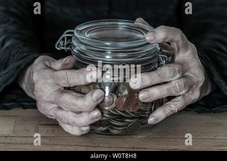 Haende einer alten Frau mit ein- Einmachglas Kleingeld. Banque D'Images