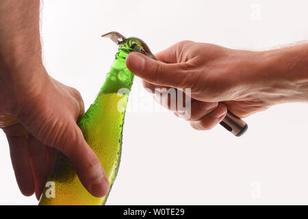 L'ouverture d'une bouteille en verre vert avec un ouvre-bouteille en métal et blanc fond isolé. Composition horizontale. Vue de face. Banque D'Images