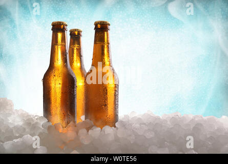 Trois bouteilles de bière plein sur de la glace concassée et blue background . Composition horizontale. Vue de face. Banque D'Images