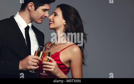 Belle jeune couple toasting with champagne at smiling contre fond gris. Banque D'Images