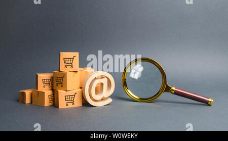 Pile de boîtes en carton avec symbole e-mail à des fins commerciales et loupe. Le magasinage en ligne et le commerce électronique. Moteur de Recherche et filtrage. acheter thro Banque D'Images