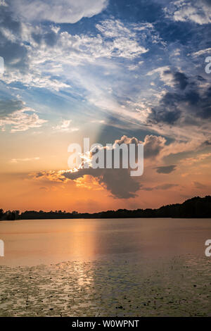 Coucher du soleil calme au lac avec les rayons du soleil dans les nuages Banque D'Images