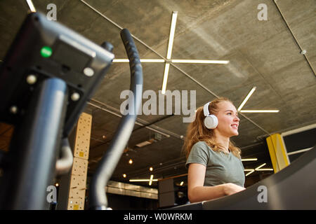 Fille termine la cardio- formation sur le tapis roulant, elle est smling Banque D'Images