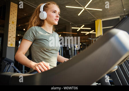 Fille termine la cardio- formation sur le tapis roulant. Banque D'Images