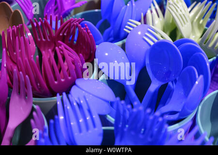 Libre bleu vif et pourpre, fourchettes et cuillères en plastique dans des gobelets en plastique Banque D'Images