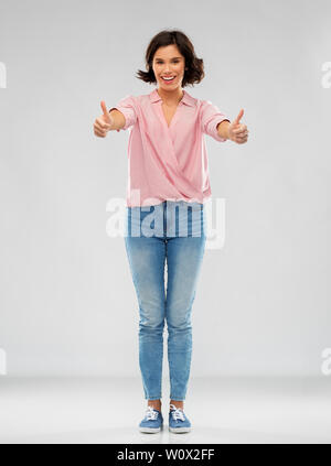 Jeune femme en jeans et chemise showing Thumbs up Banque D'Images