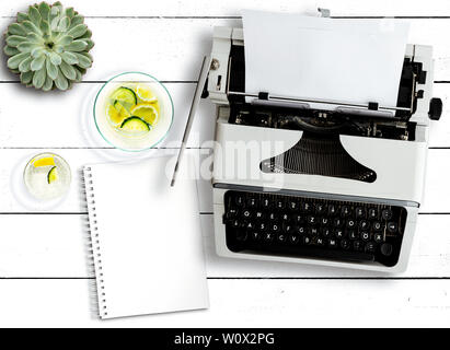 Vue de dessus de la vieille machine à écrire, plante succulente, carafe à eau et bloc-notes sur la table rustique en bois blanc Banque D'Images