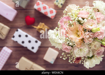 Télévision laïcs de bouquet de belles fleurs fraîches romantique avec boîte cadeau coloré présent sur fond de bois, vue du dessus Banque D'Images