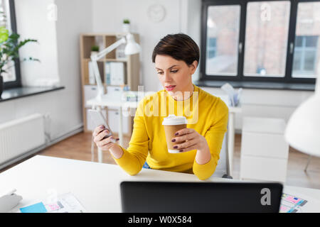 Femme avec l'aide de café au bureau smartphone Banque D'Images