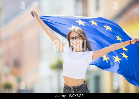 Happy Cute jeune fille avec le drapeau de l'Union européenne dans la rue quelque part en Europe. Banque D'Images