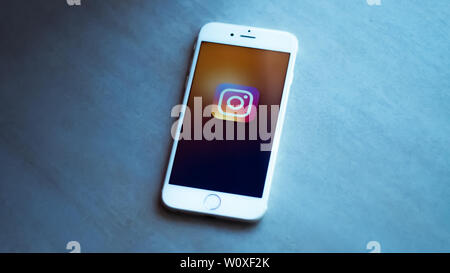 New York / Usa 06-27-2019 : un smartphone blanc avec l'icône du réseau social instagram est représenté reposant sur un fond noir en gris. Banque D'Images