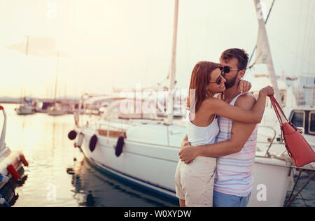 Jeune couple romantique sur le dock au coucher du soleil. Banque D'Images