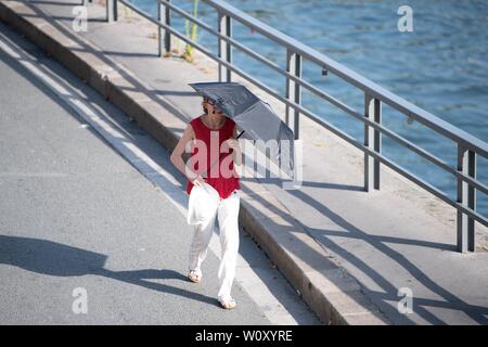 Paris, France. 27 Juin, 2019. Une femme entre avec un parasol à Paris, France, le 27 juin 2019. Le centre météorologique national, Meteo France, le jeudi a averti de "pic de chaleur exceptionnelle" le 28 juin, en plaçant 4 régions du sud sur l'alerte rouge, l'alerte maximale sur le système à l'échelle 4, et exhorte les résidents à être extrêmement vigilants. Alors que 76 autres régions, sauf la Bretagne, dans le nord-ouest de la France, restent sur alerte orange jusqu'à la semaine prochaine. Crédit : Jack Chan/Xinhua/Alamy Live News Banque D'Images