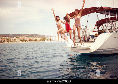 Jeune femme sautant de bateau à voile en mer. Banque D'Images