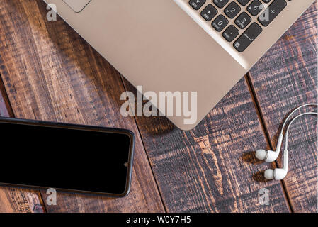 Éléments technologiques actuelles,ordinateur portable téléphone mobile et casque sur une table en bois rustique Banque D'Images