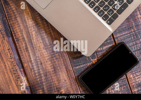 Les éléments technologiques actuels ordinateur portable et téléphone mobile sur une table en bois rustique Banque D'Images