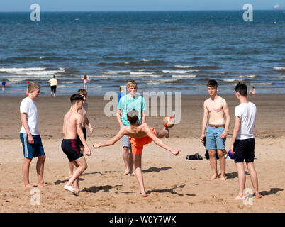 Portobello, Ecosse, Royaume-Uni. 28 Juin, 2019. Les températures chaudes et soleil ininterrompue ont amené des centaines de personnes et les familles à profiter de cette célèbre plage en dehors de Paris. Adolescents jouant au football sur la plage. Credit : Iain Masterton/Alamy Live News Banque D'Images