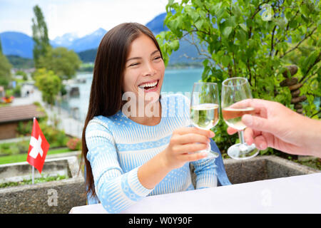 Les gens ayant du plaisir de boire le vin blanc au dîner de rire. Romantic couple sitting at table in Alpes suisses par le lac en Suisse. Romantic couple toasting bénéficiant du vin. Banque D'Images