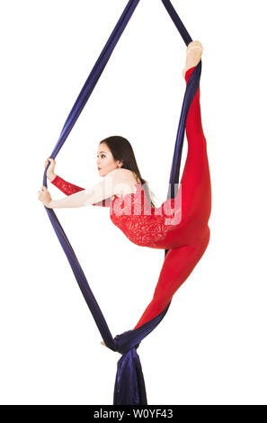 Une jeune femme aux cheveux longs en costume rouge effectue des exercices de gymnastique et de cirque sur la soie. Prise de vue en studio sur fond blanc, image isolée. Banque D'Images