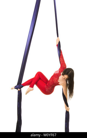 Une jeune femme aux cheveux longs en costume rouge effectue des exercices de gymnastique et de cirque sur la soie. Prise de vue en studio sur fond blanc, image isolée. Banque D'Images