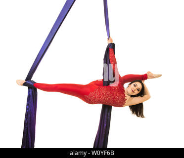 Une jeune femme aux cheveux longs en costume rouge effectue des exercices de gymnastique et de cirque sur la soie. Prise de vue en studio sur fond blanc, image isolée. Banque D'Images