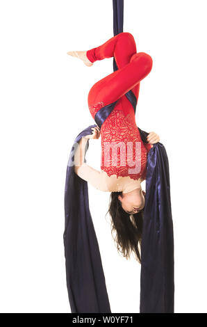 Une jeune femme aux cheveux longs en costume rouge effectue des exercices de gymnastique et de cirque sur la soie. Prise de vue en studio sur fond blanc, image isolée. Banque D'Images