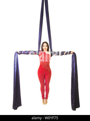 Une jeune femme aux cheveux longs en costume rouge effectue des exercices de gymnastique et de cirque sur la soie. Prise de vue en studio sur fond blanc, image isolée. Banque D'Images