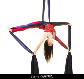 Une jeune femme aux cheveux longs en costume rouge effectue des exercices de gymnastique et de cirque sur la soie. Prise de vue en studio sur fond blanc, image isolée. Banque D'Images