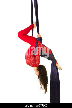 Une jeune femme aux cheveux longs en costume rouge effectue des exercices de gymnastique et de cirque sur la soie. Prise de vue en studio sur fond blanc, image isolée. Banque D'Images