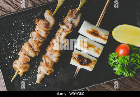 De style japonais, la peau de poulet brochettes yakitori grillés ou servir dans l'izakaya avec éclairage de plaque gris. Banque D'Images