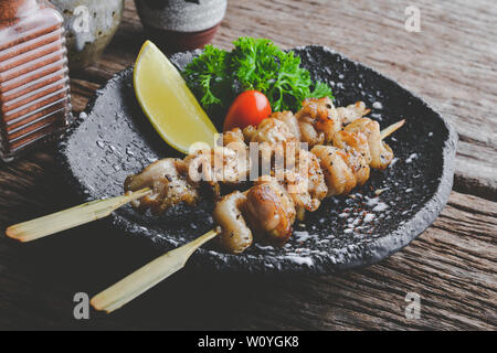 De style japonais, la peau de poulet brochettes yakitori grillés ou servir dans l'izakaya avec éclairage de plaque gris. Banque D'Images