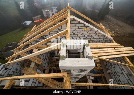 Vue de dessus du châssis de toit en bois poutres de bois et de planches sur les parois en blocs isolants en mousse creux. Bâtiment, construction, toitures et renovat Banque D'Images