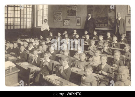 Carte postale édouardienne de junior ou de l'enfant école des garçons en classe portant leurs plus beaux habits du dimanche, colliers, empesés fruits modélisation avec de l'argile, homme et femmes de l'école les enseignants, les maîtres, Royaume-Uni, vers 1910 Banque D'Images