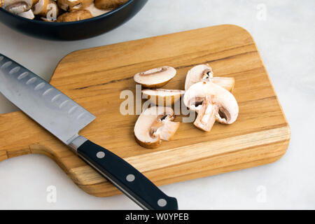 Champignons Cremini trancher sur une planche à découper en bois Banque D'Images