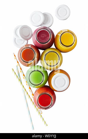 Vue aérienne sur un assortiment de bouteilles de jus de couleurs différentes à côté de white caps et des pailles isolées sur fond blanc Banque D'Images