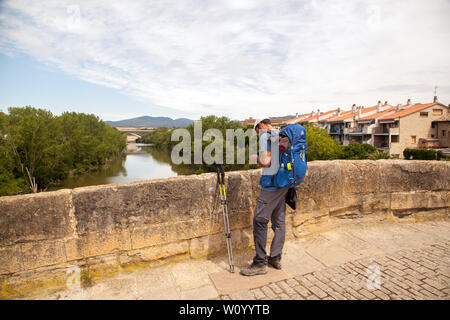 Homme Pilgrim en marchant sur le pont médiéval dans la ville espagnole de Puente la Reina tout en marchant sur la route de pèlerinage Camino de Santiago Espagne Banque D'Images