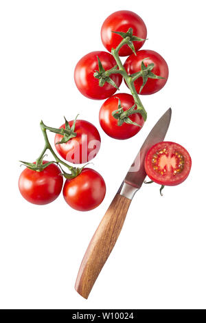 Grappes de tomates rouges mûres fraîches sur la vigne à l'aide d'un petit couteau de cuisine et de moitié la pulpe juteuse tomate montrant isolated on white Banque D'Images