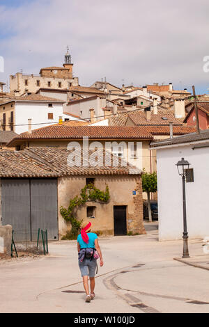 Femme pèlerine marchant dans la campagne espagnole sur le Camino de Santiago le chemin de St James approchant le village de Cirauqui Navarra Espagne Banque D'Images