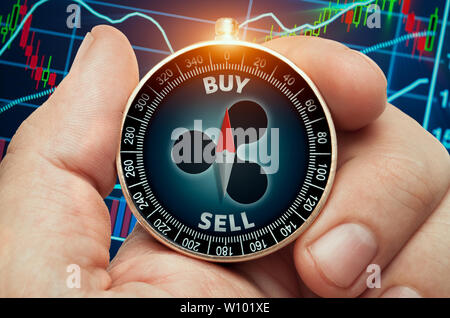 Hand holding compass avec symbole d'ondulation rougeoyant et devant les données de la bourse. Aiguille de la boussole montrant buy word. Banque D'Images