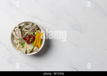 Soupe aux nouilles chauffée avec du boeuf, champignons et légumes sur fond blanc. L'espace de copie pour le texte. Banque D'Images
