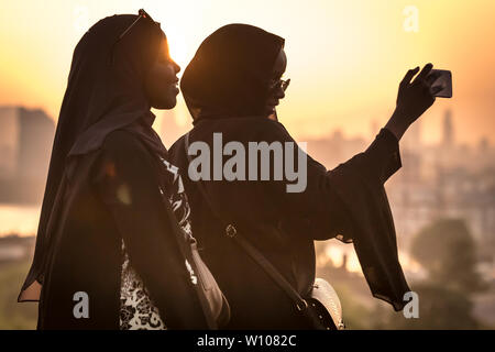 Londres, Royaume-Uni. 28 Juin, 2019. Météo France : les jeunes filles profiter d'un coucher de soleil spectaculaire depuis le haut de la ville de Greenwich Park comme températures canicule devraient dépasser 31C au cours de la semaine. Crédit : Guy Josse/Alamy Live News Banque D'Images