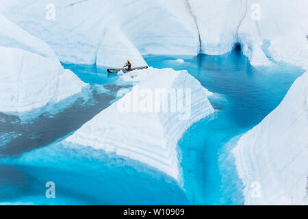 Un jeune homme et de l'escalade sur glace à travers les palettes guide un canyon étroit derrière un morceau de glace de glacier blanc ressemblant à un iceberg. Cette fin n'est qu'surroun Banque D'Images