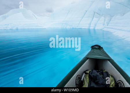 Jusqu'à présent la Matanuska Glacier en Alaska un canoë gonflable flotte sur un lac d'un bleu profond sur le dessus du glacier. Banque D'Images