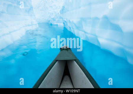 Canoë à travers une crevasse remplie d'eau de l'eau glaciaire d'un bleu profond sur le dessus de la Matanuska Glacier en Alaska. La piscine ou le lac bleu glacier avec w Banque D'Images