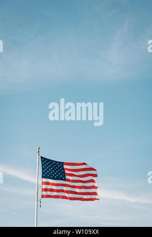 Un drapeau américain en vol avec un ciel bleu Banque D'Images