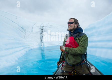 Un lac (lac supraglaciaire sur le dessus de la glace de glacier) lorsqu'un grimpeur sur glace a permis un canoë gonflable à barboter dans l'eau d'un bleu profond Banque D'Images