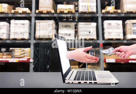 Ordinateur portable à partir de la main pour obtenir de l'argent et d'un hand holding US dollar pour payer sur le stock d'affaires en ligne .fond étagères concept. Banque D'Images