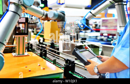 Contrôle de l'ingénieur et de contrôle des armements robot automatisation de verre disposés sur la bouteille d'eau dans l'équipement automatique machines industrielles factory de la ligne de production Banque D'Images