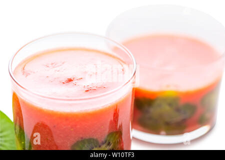 Close up of strawberry smoothie en verre transparent décoré de fraises et de kiwis isolé sur fond blanc Banque D'Images